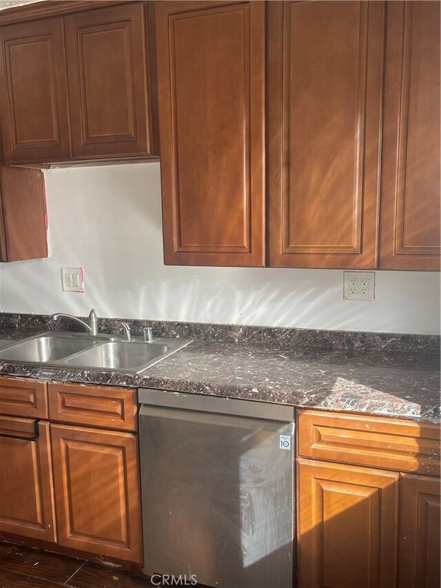 kitchen with dark stone countertops, sink, and stainless steel dishwasher