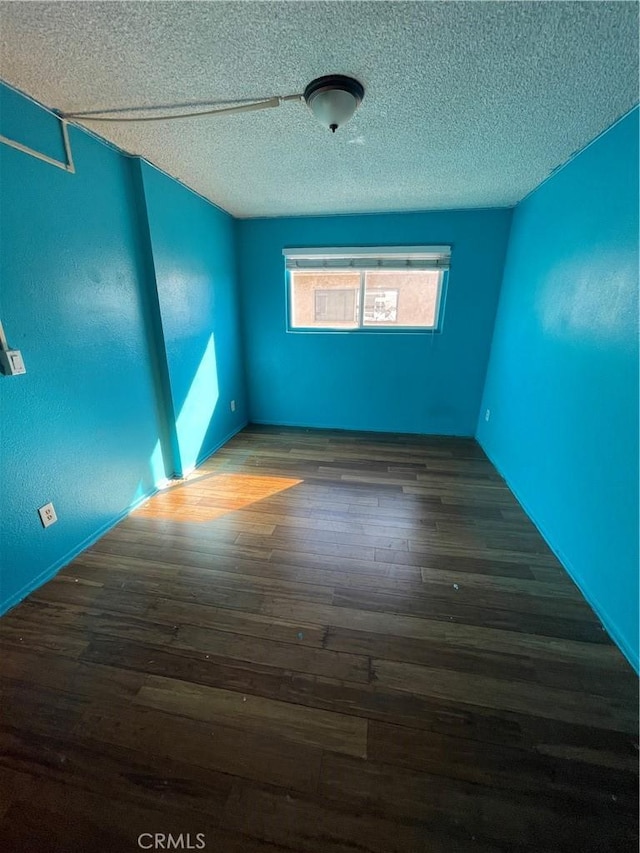 spare room with dark hardwood / wood-style floors and a textured ceiling