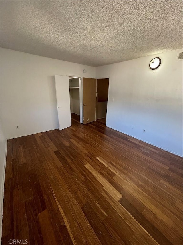 unfurnished bedroom featuring a closet, dark hardwood / wood-style flooring, and a textured ceiling