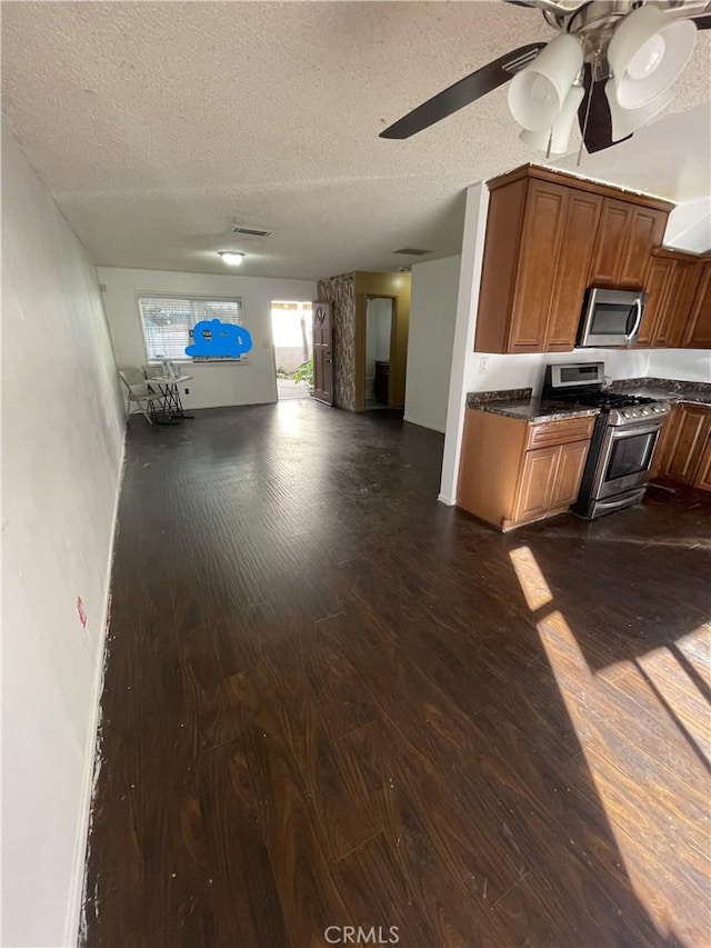 kitchen featuring ceiling fan, dark wood-type flooring, a textured ceiling, and appliances with stainless steel finishes