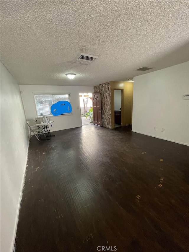 empty room with dark hardwood / wood-style floors and a textured ceiling