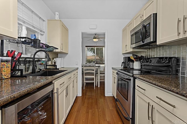 kitchen featuring sink, dark stone countertops, wine cooler, decorative backsplash, and stainless steel appliances