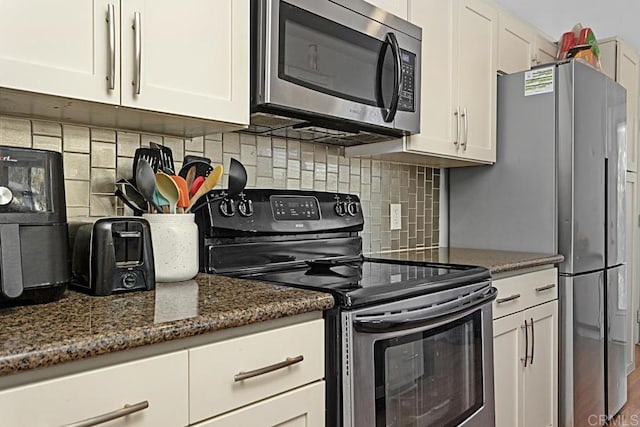 kitchen featuring dark stone countertops, white cabinets, appliances with stainless steel finishes, and backsplash