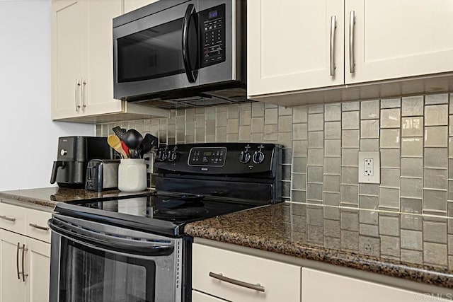 kitchen featuring electric stove, dark stone countertops, and white cabinets