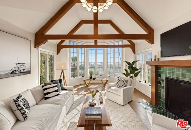 living room with a tile fireplace, high vaulted ceiling, a healthy amount of sunlight, and light hardwood / wood-style floors