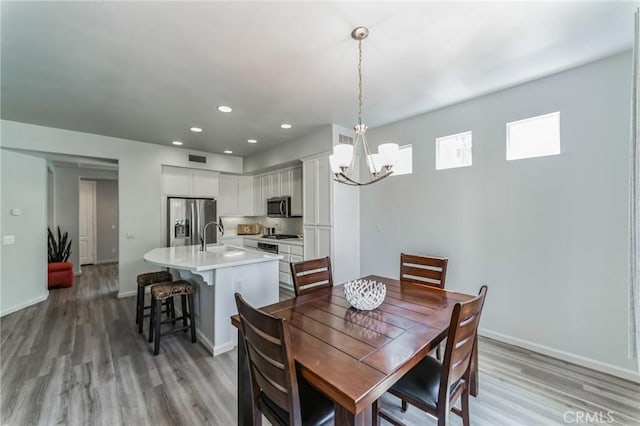 dining area featuring light hardwood / wood-style floors, sink, and a chandelier