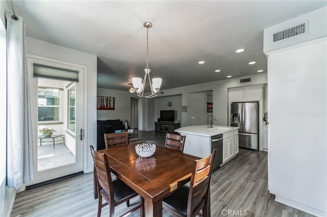 dining room featuring sink, an inviting chandelier, and light wood-type flooring