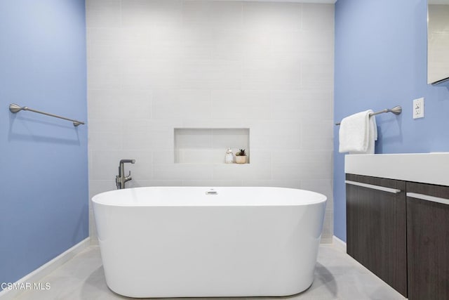 bathroom with a tub to relax in, vanity, and tile walls