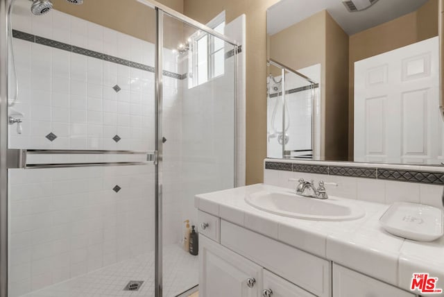 bathroom featuring vanity, a shower with door, and backsplash