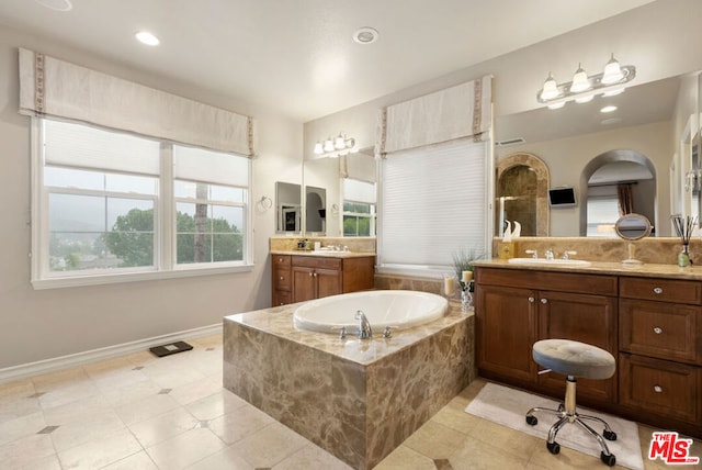 bathroom with tiled tub, tile patterned flooring, and vanity