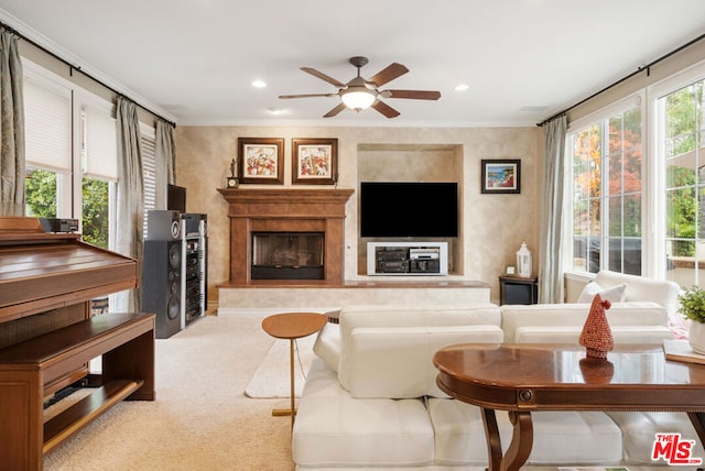 living room with a wealth of natural light, crown molding, ceiling fan, and light carpet