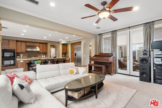 living room with ceiling fan, sink, ornamental molding, and light carpet