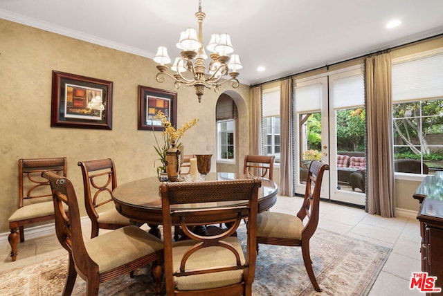 dining room with light tile patterned flooring, ornamental molding, and an inviting chandelier