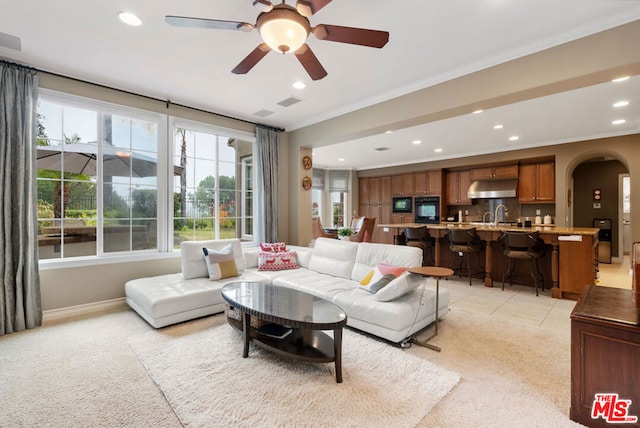 living room with ceiling fan, sink, and crown molding