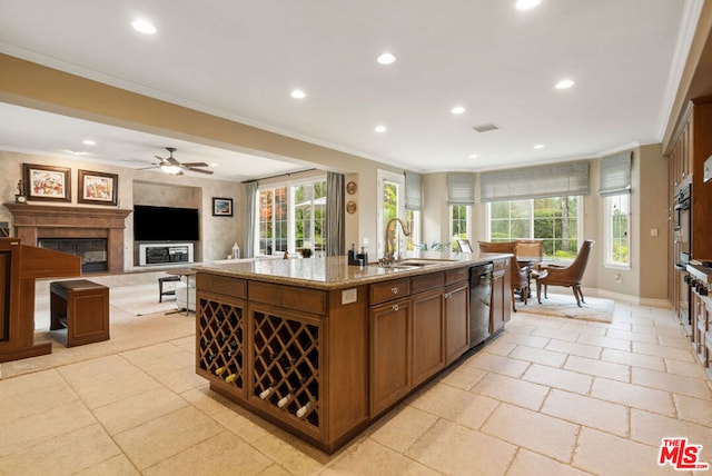 kitchen with a healthy amount of sunlight, stainless steel dishwasher, crown molding, and an island with sink