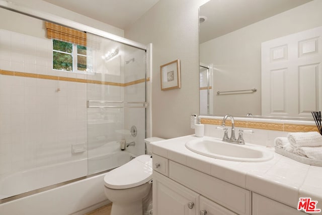 full bathroom featuring vanity, enclosed tub / shower combo, and toilet