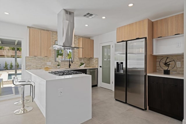 kitchen with sink, island range hood, decorative backsplash, and appliances with stainless steel finishes