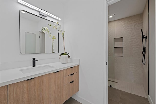 bathroom with a tile shower, vanity, and tile patterned flooring