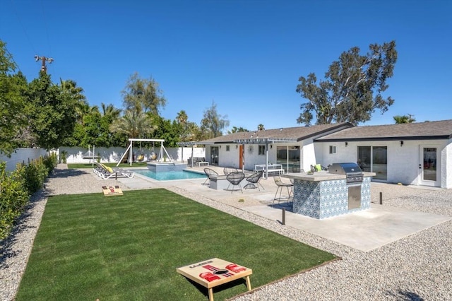 view of pool with area for grilling, a patio area, a lawn, and exterior kitchen