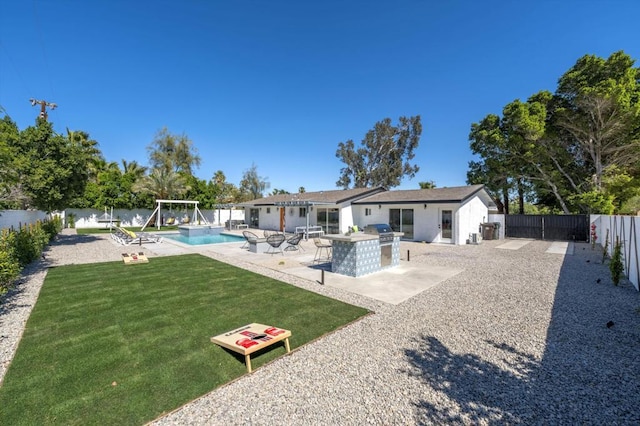 rear view of house with a fenced in pool, a yard, and a patio area