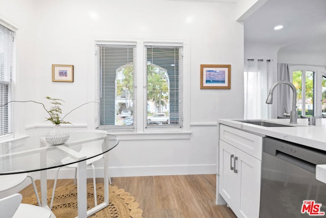 kitchen with white cabinets, light hardwood / wood-style floors, stainless steel dishwasher, and a healthy amount of sunlight