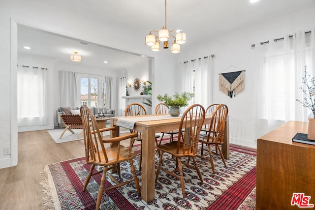 dining area with light hardwood / wood-style floors and a chandelier