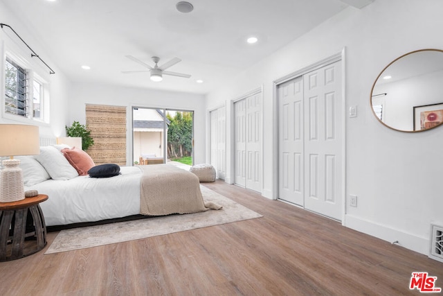 bedroom featuring multiple closets, ceiling fan, and hardwood / wood-style flooring