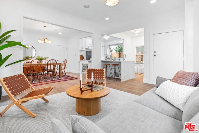 living room with light wood-type flooring, sink, and a chandelier