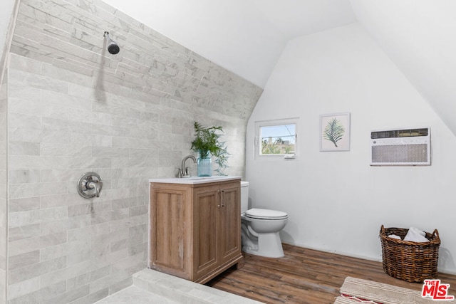 bathroom with hardwood / wood-style floors, vanity, a wall mounted air conditioner, lofted ceiling, and a tile shower