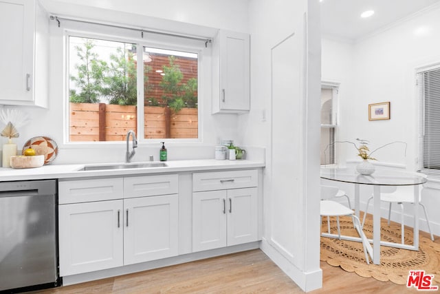 interior space featuring stainless steel dishwasher, crown molding, sink, light hardwood / wood-style floors, and white cabinetry