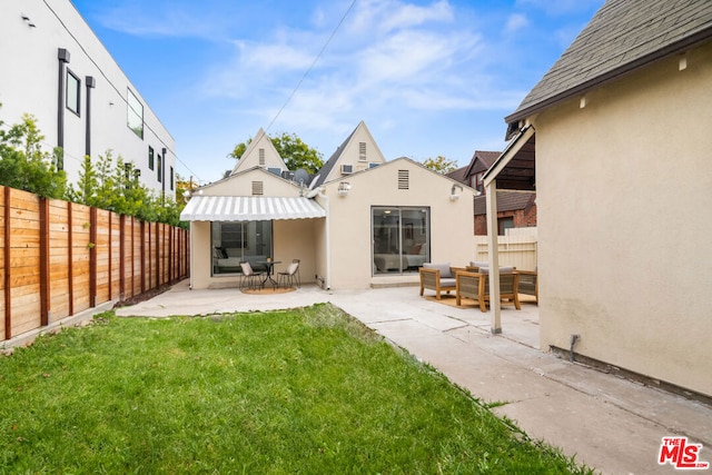 back of house with a lawn, an outdoor living space, and a patio area