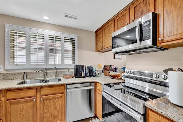 kitchen featuring light stone counters, sink, and stainless steel appliances