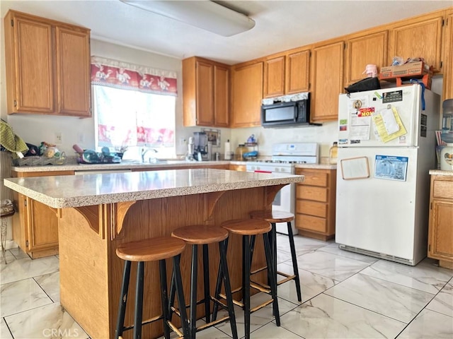 kitchen with a kitchen bar, sink, white appliances, and a center island