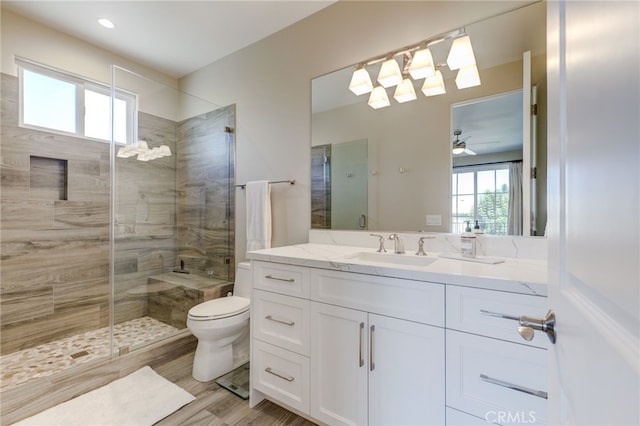 bathroom featuring ceiling fan, walk in shower, toilet, vanity, and hardwood / wood-style flooring