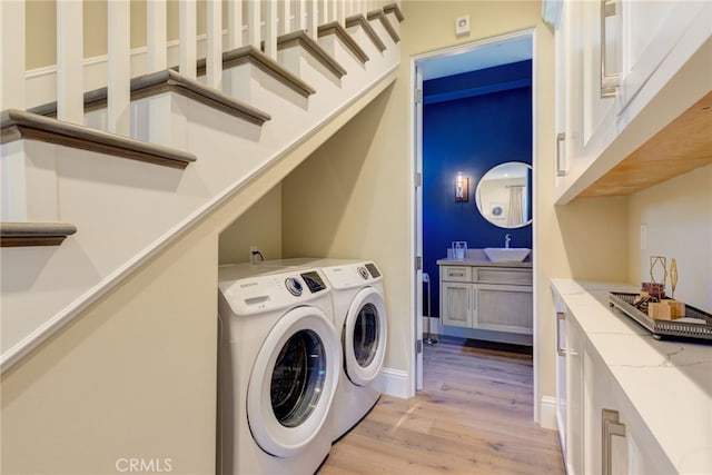 laundry room featuring washing machine and dryer, sink, and light hardwood / wood-style floors