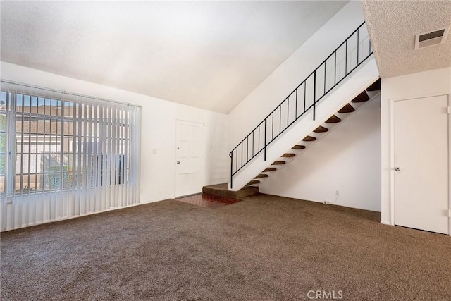 unfurnished living room with dark colored carpet and lofted ceiling