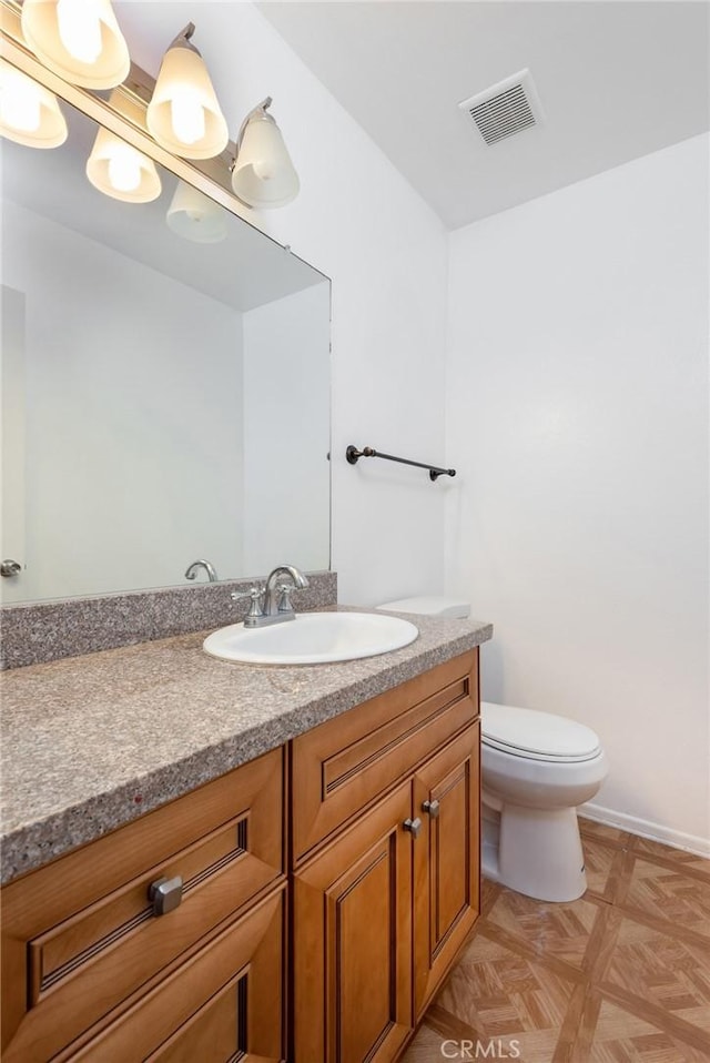 bathroom with toilet, parquet floors, and vanity