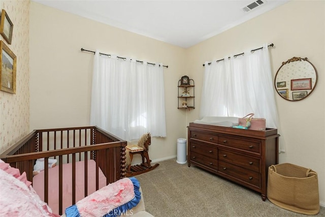 bedroom featuring light colored carpet, multiple windows, and a nursery area