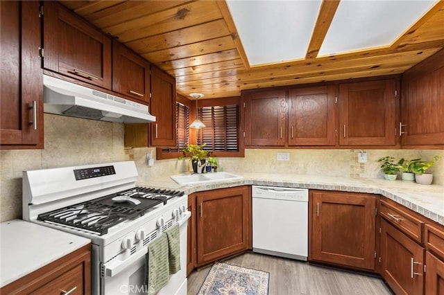 kitchen with decorative light fixtures, sink, backsplash, light hardwood / wood-style floors, and white appliances