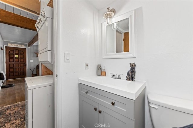 bathroom featuring vanity, stacked washer / drying machine, and toilet