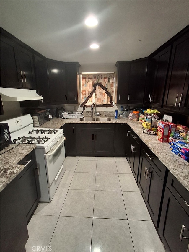 6100 Rugby Ave Unit 207, Huntington Park, CA 90255 - kitchen featuring a sink, white gas stove, under cabinet range hood, dark cabinetry, and light stone counters