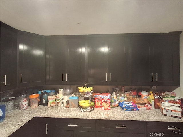 kitchen featuring light stone countertops and dark brown cabinetry