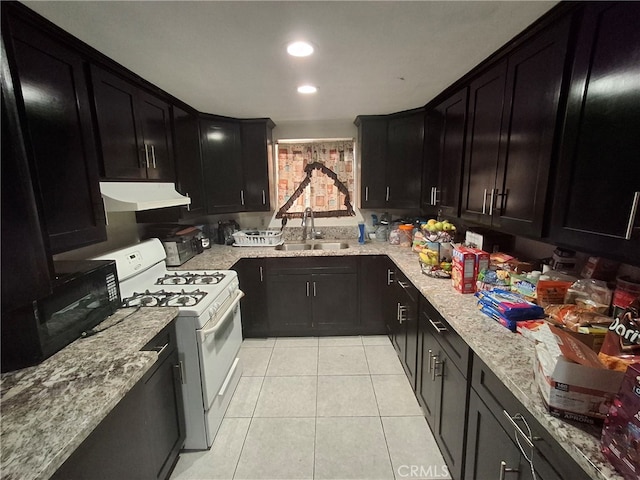 kitchen featuring light tile patterned flooring, light stone counters, white range with gas stovetop, and sink