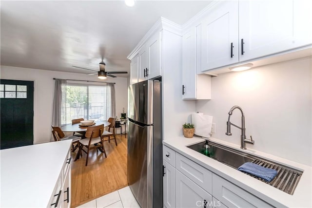 kitchen featuring light wood-type flooring, white cabinetry, stainless steel refrigerator, and ceiling fan