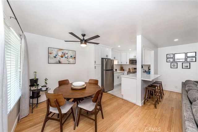 dining space with ceiling fan and light hardwood / wood-style flooring