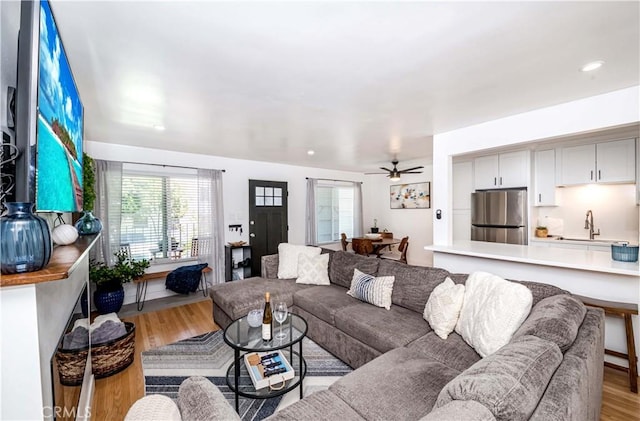 living room featuring light hardwood / wood-style floors, ceiling fan, and sink