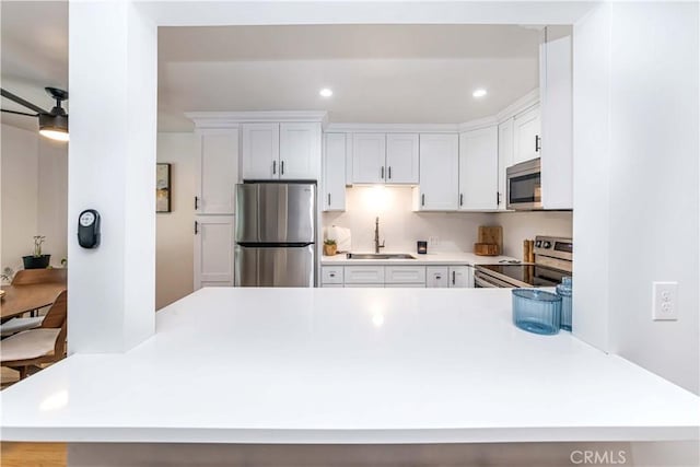 kitchen featuring white cabinets, sink, kitchen peninsula, and stainless steel appliances