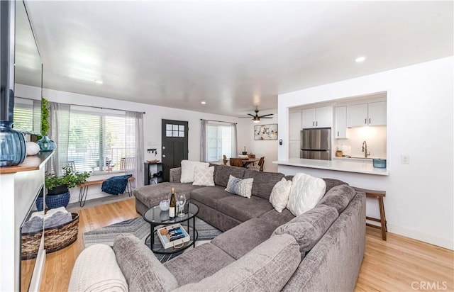 living room featuring ceiling fan, light hardwood / wood-style floors, and sink