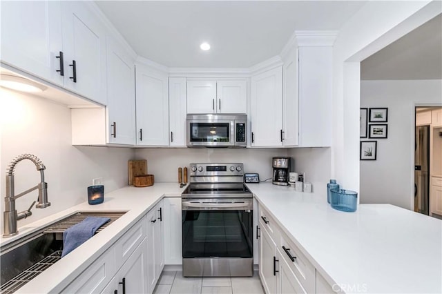 kitchen with light tile patterned floors, stainless steel appliances, white cabinetry, and sink