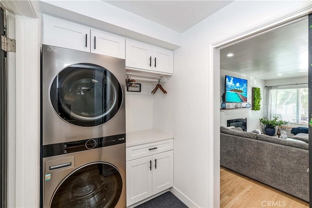 laundry area featuring stacked washer and clothes dryer and light wood-type flooring